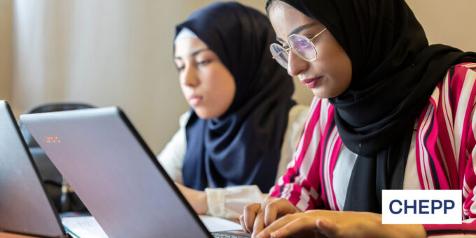 Two women sitting next to each other working on laptop computers