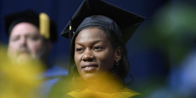 Woman wearing regalia looking off into the distance