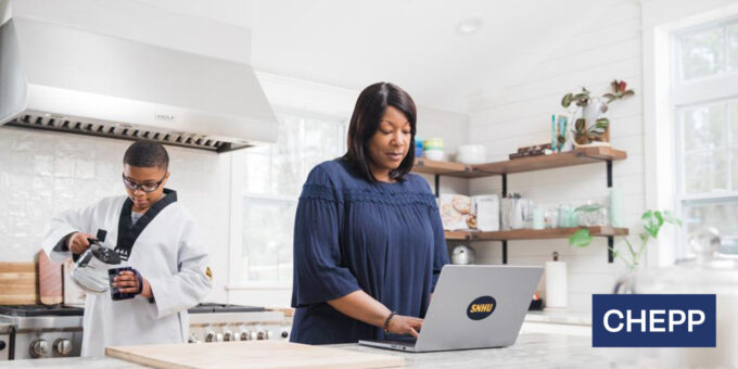 Family in kitchen, mother on laptop, son pouring a mug of water