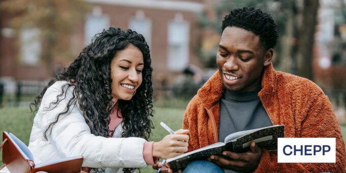 Two people sitting next to each other smiling and looking at a notebook