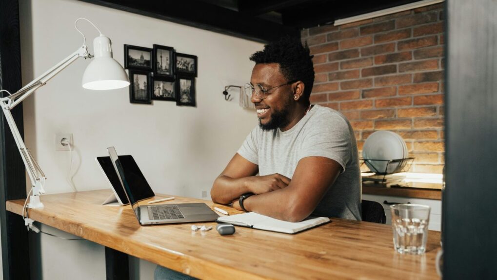 Person sitting at a desk on their laptop, smiling