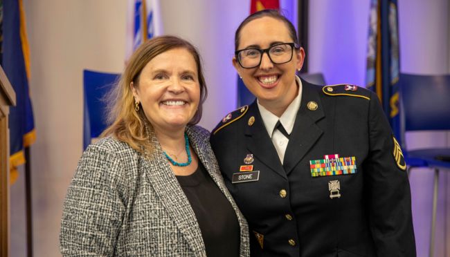 SNHU President Lisa Marsh Ryerson smiling at the camera with an SNHU student in a military uniform