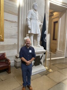 Daniel standing and smiling in front of a white marble statue