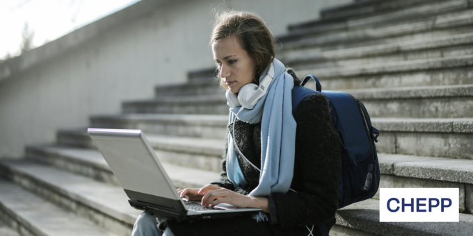 Person sitting on stairs typing on a laptop in their lap.