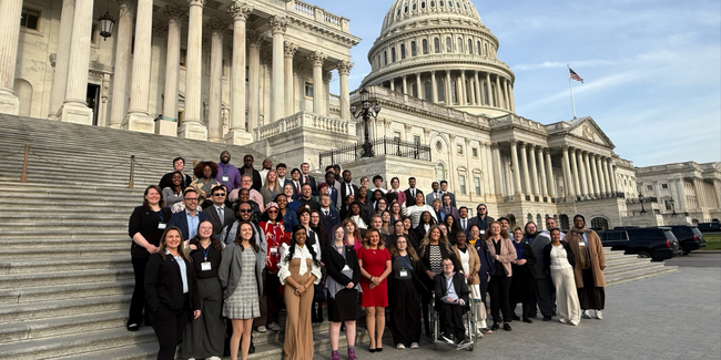 A group of students on a set of stairs in front of a government building.